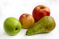Three apples of different sizes and colors and a green ripe pear on a white background Royalty Free Stock Photo