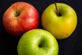 Three apples, one green and two red and yellow on a dark background Royalty Free Stock Photo