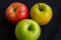 Three apples, one green and two red and yellow on a dark background Royalty Free Stock Photo