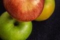 Three apples, one green and two red and yellow on a dark background Royalty Free Stock Photo