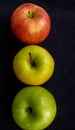 Three apples, one green and two red and yellow on a dark background Royalty Free Stock Photo