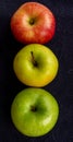 Three apples, one green and two red and yellow on a dark background Royalty Free Stock Photo