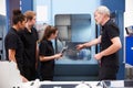 Three Apprentices Working With Engineer On CNC Machinery