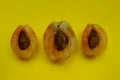 Three apricot halves over yellow background. Abstract food background.