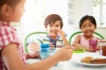 Three Asian Children Having Breakfast Together In Kitchen