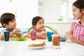 Three Asian Children Having Breakfast Together In Kitchen