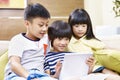 Three asian children using digital tablet together