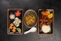 Three Asian cuisine dishes with side dishes on a black background Royalty Free Stock Photo