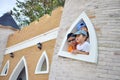 Three asian kids show their head through castle's tower in the s