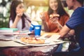 Three Asian people enjoy eating pizza at outdoors after tutoring class. Education and party concept. Food and Drinks theme. Royalty Free Stock Photo