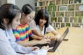 Three asian teenager using laptop computer in home living room Royalty Free Stock Photo
