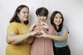 Three Asian women feel happy and a romantic shapes heart gesture expresses tender feelings, close friendship concept