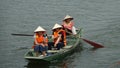 Three Asian women paddling a wooden boat along the scenic river in Vietnam.