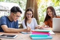 Three Asian young campus students enjoy tutoring and reading books together. Friendship and Education concept. Campus school and