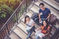 Three Asian young campus students enjoy tutoring and reading books together at stair. Friendship and Education concept. Campus Royalty Free Stock Photo