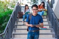 Three Asian young campus students enjoy tutoring and reading books together at stair. Friendship and Education concept. Campus Royalty Free Stock Photo