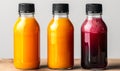 Three assorted fresh fruit juices in glass bottles with black caps on a neutral background, representing healthy dietary Royalty Free Stock Photo