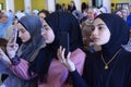 Three attractive Muslim girls taking pictures with mobile phones at the same time during Woman International Forum