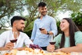 Three attractive young happy people celebrating outdoor holding red wine glasses - Stylish millennial friends having fun in the Royalty Free Stock Photo