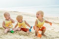 Three baby Toddler sitting on a tropical beach in Thailand and playing with sand toys. The yellow shirts. Two boys and one girl Royalty Free Stock Photo