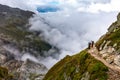 Three backpackers standing mountain trail looking at beautiful view Royalty Free Stock Photo