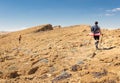 Three backpackers walking ascending mountain rock desert slope. Royalty Free Stock Photo