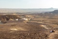 Three backpackers walking stone desert trail.