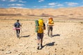 Three backpackers walking stone desert trail. Royalty Free Stock Photo