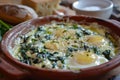 Three baked eggs over spinach in ceramic dish. AI generated Royalty Free Stock Photo