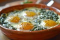 Three baked eggs over spinach in ceramic dish. Neural network AI generated Royalty Free Stock Photo
