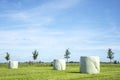 Three bales of hay, silage bales, wrapped in light green plastic stacked in a landscape, the horizon and blue skies Royalty Free Stock Photo