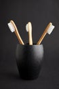 Three bamboo toothbrushes in a black glass