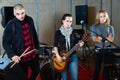 Three bandmates posing together with musical instruments in rehe Royalty Free Stock Photo