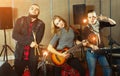 Three bandmates posing together with musical instruments in rehe Royalty Free Stock Photo