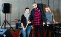 Three bandmates posing together with musical instruments in rehearsal room Royalty Free Stock Photo