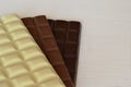 three bars of chocolate lie on a white wooden table