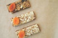 Three bars with muesli and dried apricots on a background of parchment healthy food breakfast