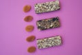 Three bars with muesli and dried apricots on a background of pink paper healthy food breakfast macro photo