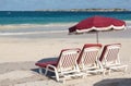 Three beach loungers and umbrella on sand