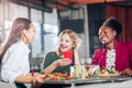 Three beaming stylish women spending funny evening together