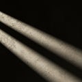Three beams of light illuminate a textured, slightly speckled surface against a stark, Royalty Free Stock Photo