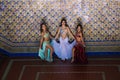 Three beautiful adult belly dancers are posing and dancing for the camera. The dancers are dressed in typical belly dance costumes