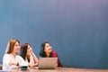 Three beautiful Asian girls looking upward to copy space while working at cafe, modern lifestyle with gadget technology concept