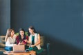 Three beautiful Asian girls using smartphone and laptop, chatting on sofa together at cafe with copy space Royalty Free Stock Photo