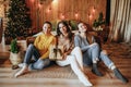 Three beautiful cheerful happy young girls girlfriend give Christmas gifts on the background of a new year tree at home Royalty Free Stock Photo