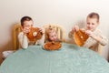 Three beautiful children sit at table in the kitchen and eat large round pancakes. Carnival Festival Royalty Free Stock Photo