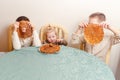 Three beautiful children sit at table in the kitchen and eat large round pancakes. Carnival Festival Royalty Free Stock Photo