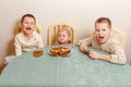 Three beautiful children sit at table in the kitchen and eat large round pancakes. Carnival Festival Royalty Free Stock Photo