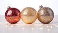 Three beautiful Christmas ornaments in red, gold, and silver with a white background and twinkling lights Royalty Free Stock Photo