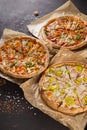 three beautiful colorful juicy different pizzas lie on parchment Royalty Free Stock Photo